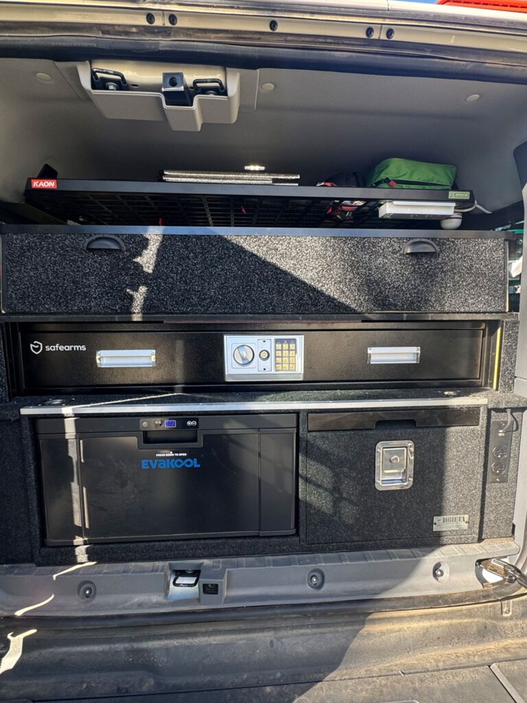 The custom cabinetry rear compartment houses an electronic digital safe box positioned above the storage drawer units