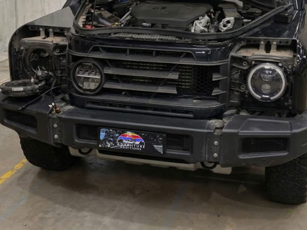 The mid-installation stage showing the precision mounting of the replacement lamp within the disassembled front grille framework