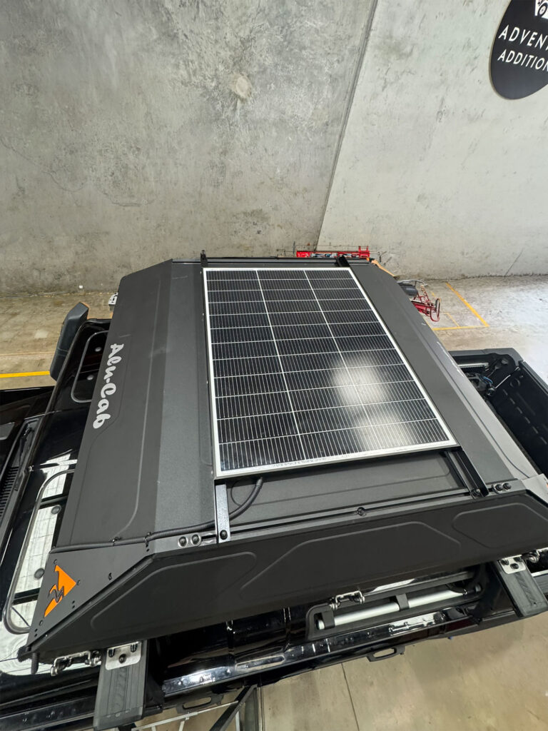 The solar panel mounts directly to the top shell of the rooftop tent to capture sunlight