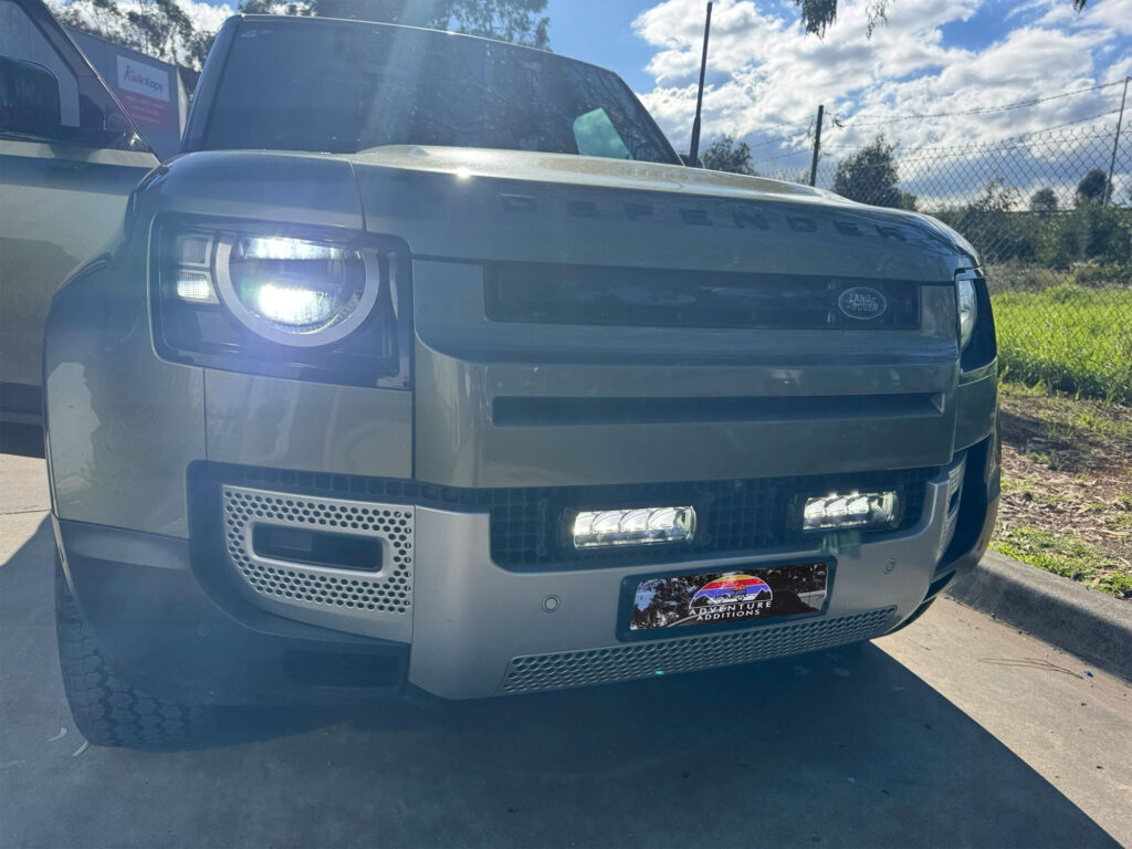 Dual Lazer Triple-R 750 LED lamps illuminated inside the lower front grille of the Land Rover Defender