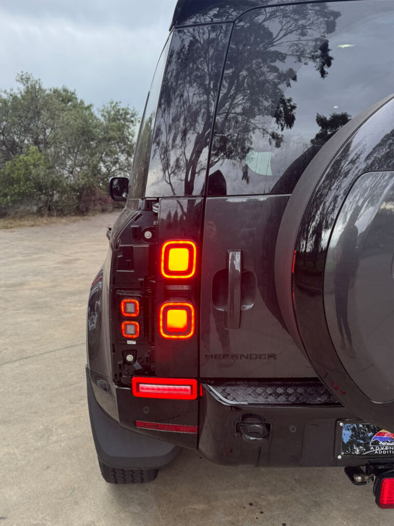 Rear view of the 2025 Land Rover Defender L663 with Smoked Full LED Tail Lights and illuminated bumper reverse lights